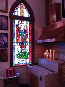 To the right side of the entrance doors- a stained glass window with his image and an area where one can light candles